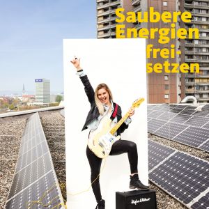 Frau spielt auf einem Dach mit Solarpanels E-Gitarre, Motto Saubere Energien freisetzen